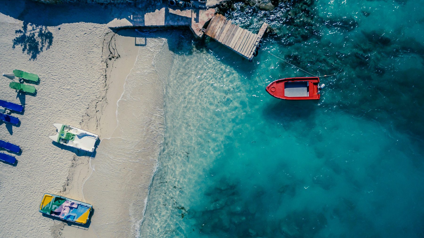 An aerial view of boats and turquoise water on a sandy beach