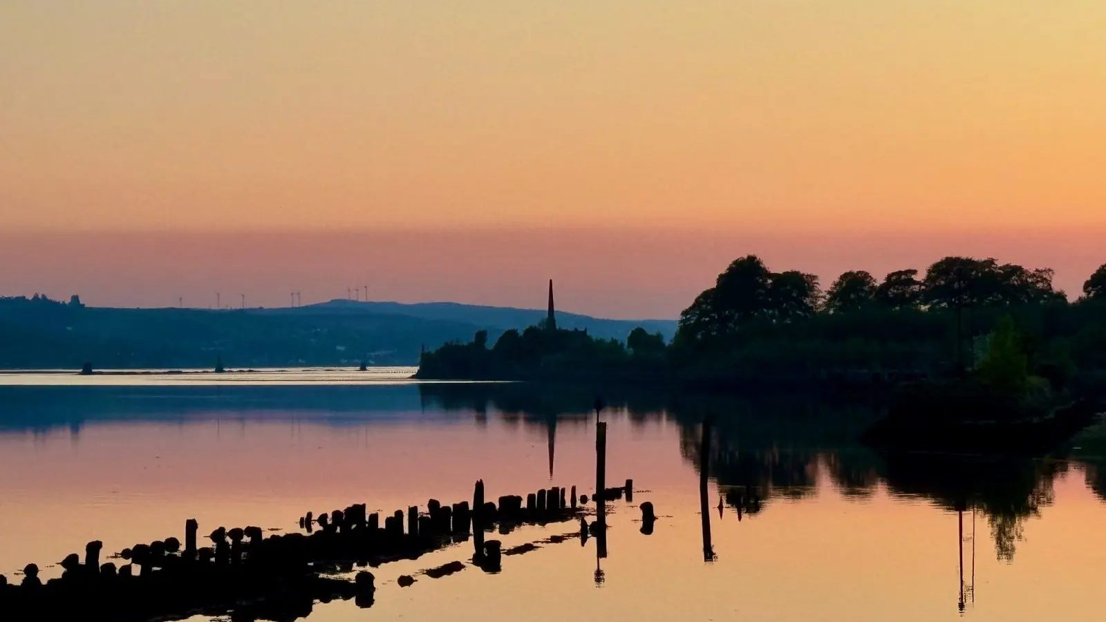 Golden sunset light over still water and an old pier in Scotland
