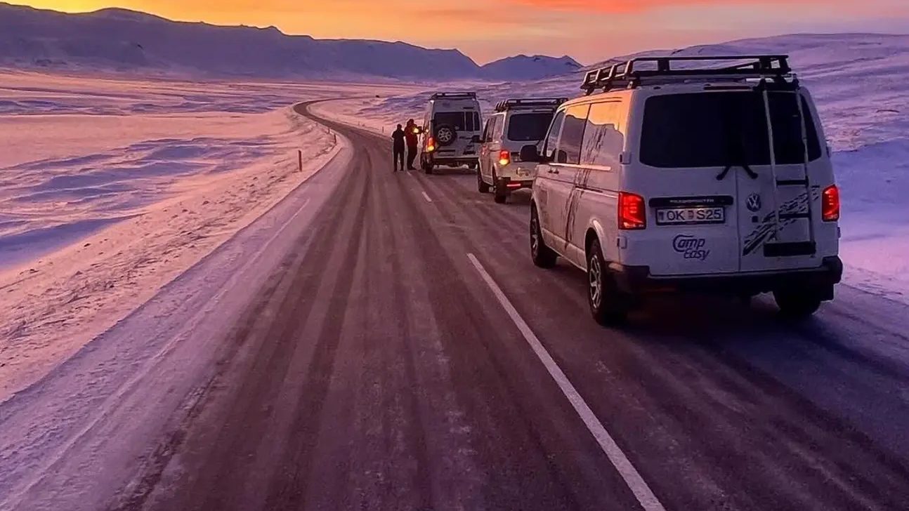 Campervans on a snowy road at sunset in Iceland