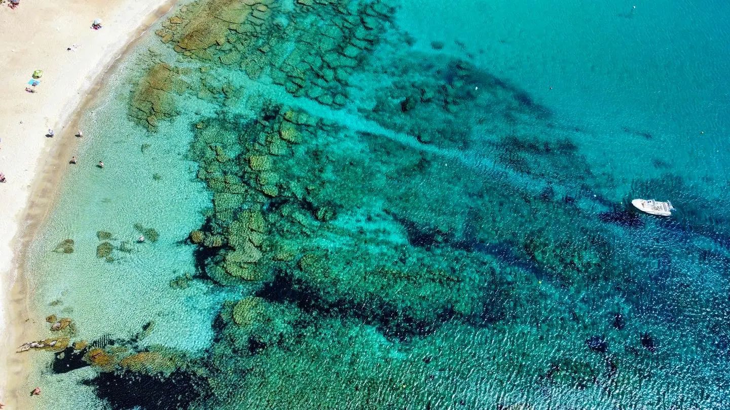 An aerial view of clear turquoise water over rocks and sand off Naxos, Greece