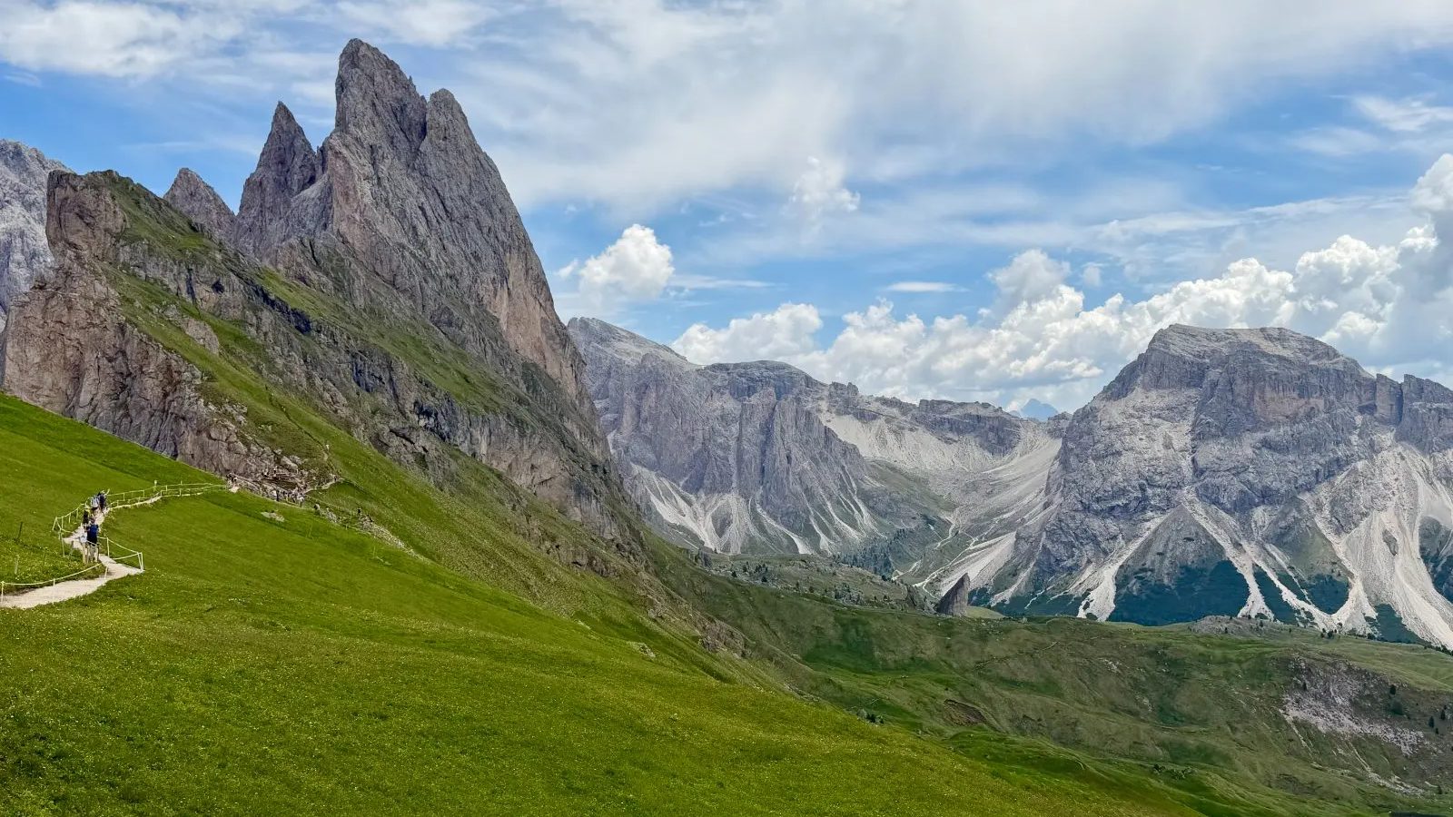 Hikers below the jagged Seceda ridge in the Dolomites in summer