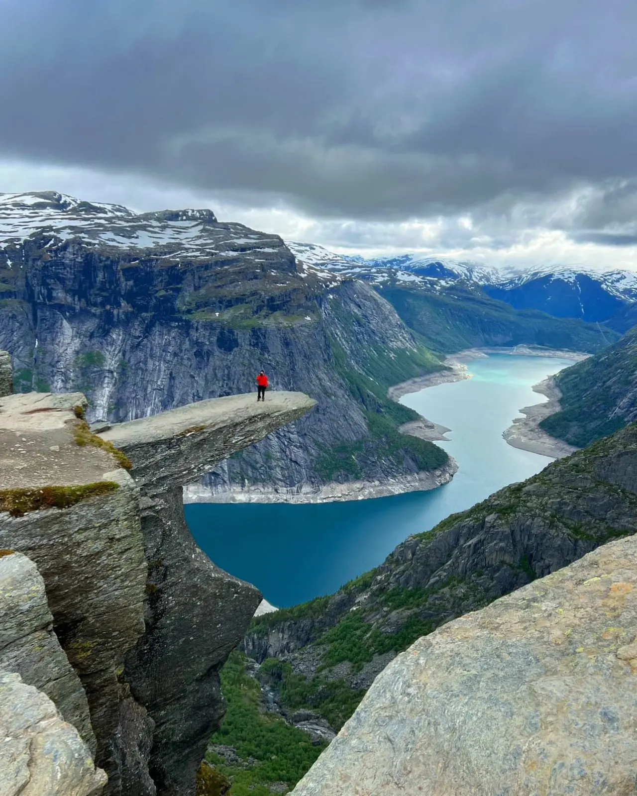 A lone figure on the Trolltunga ledge above the fjord, Norway
